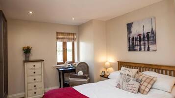 A bedroom with a bed, a desk, a chair, a dresser, and a painting on the wall.