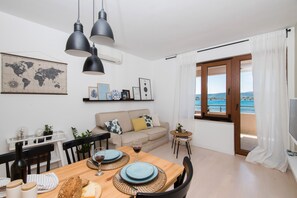 Un comedor con una mesa de madera preparada para dos personas, un mapa del mundo en la pared y vista al mar a través de un ventanal grande.