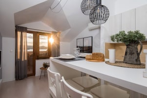 A modern kitchen with a large island, white cabinetry, and a view of the outdoors.
