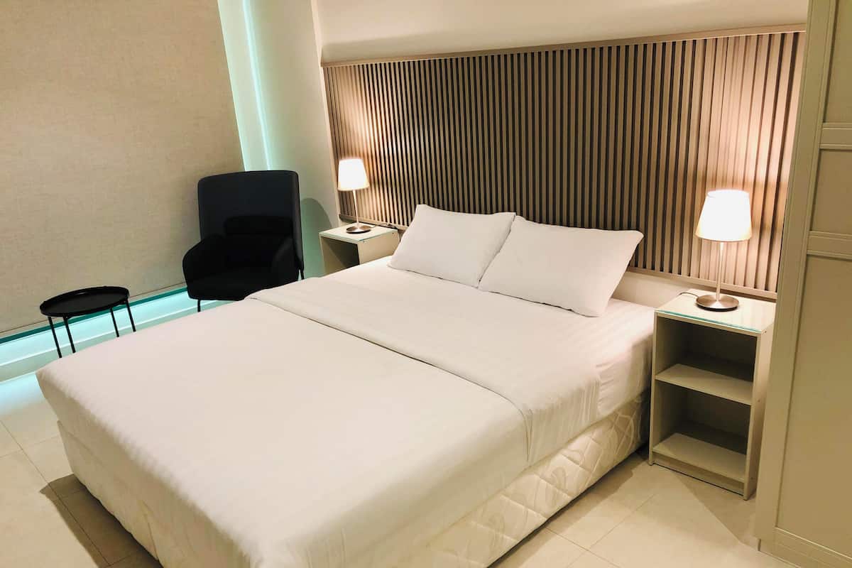 A hotel room with a large bed, two bedside tables with lamps, a chair, and a small table.