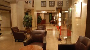 Um hall com poltronas de couro, um balcão de recepção e uma grande planta em vaso.