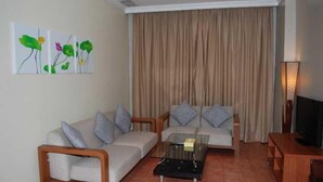 Uma sala de estar com sofá, mesa de centro de vidro e televisão.