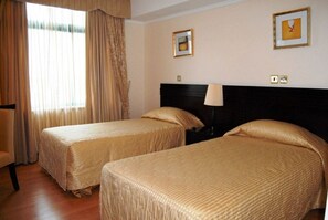 A hotel room with two beds, a chair, a lamp, and curtains. - Boma Inn (Nairobi)