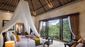 A luxurious bedroom with a canopy bed, a view of lush greenery, and a stone wall. - The Royal Pita Maha (Ubud)