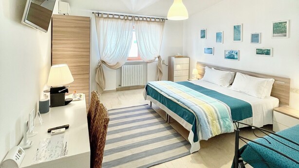 Une chambre d’hôtel comprenant un lit, une table de chevet, une lampe, une chaise, un bureau et un téléviseur.