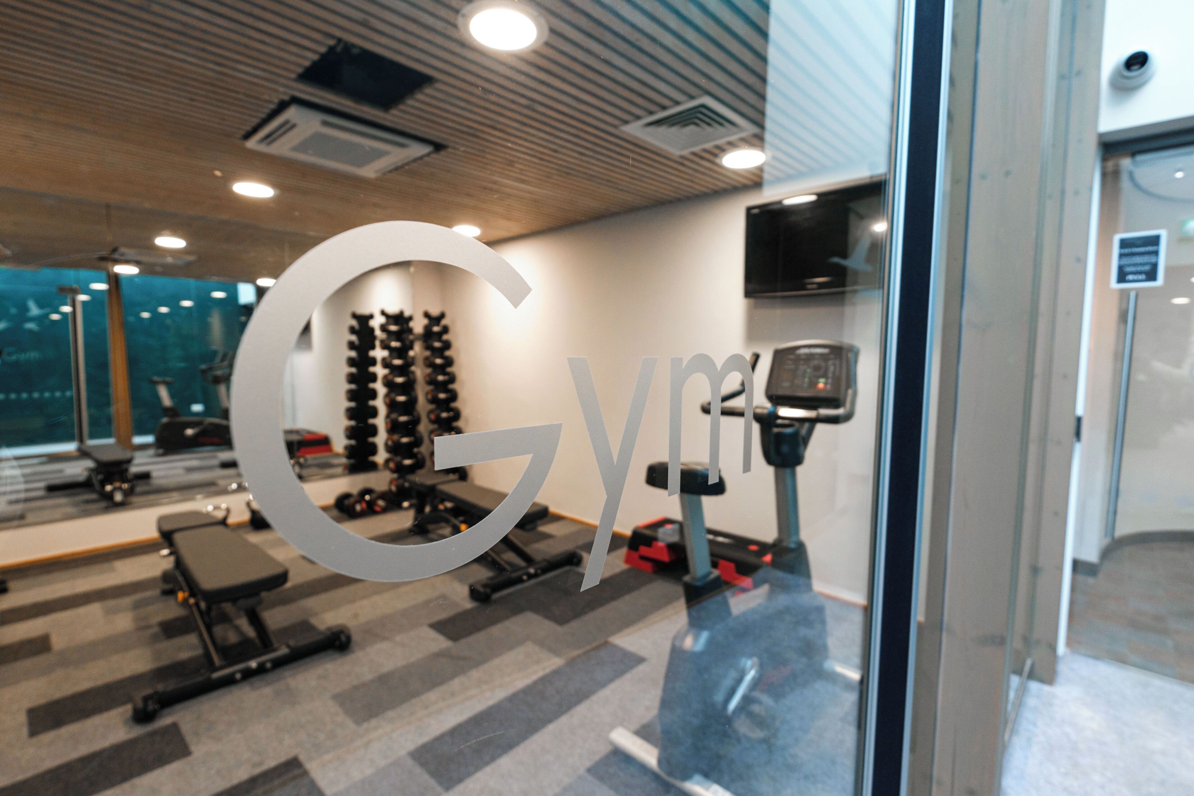 A gym with exercise equipment, a large mirror, and a ceiling with recessed lighting.