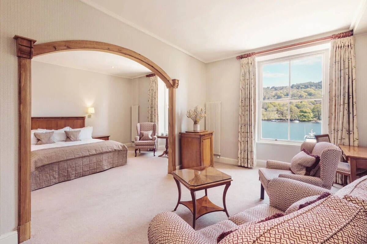 Ein Hotelzimmer mit einem großen Bett, einem Schlafsofa, einem Sessel, einem kleinen Tisch und Seeblick.