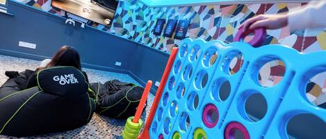 A room with a colorful geometric wall pattern, a television mounted on the wall, and a blue and orange play structure.