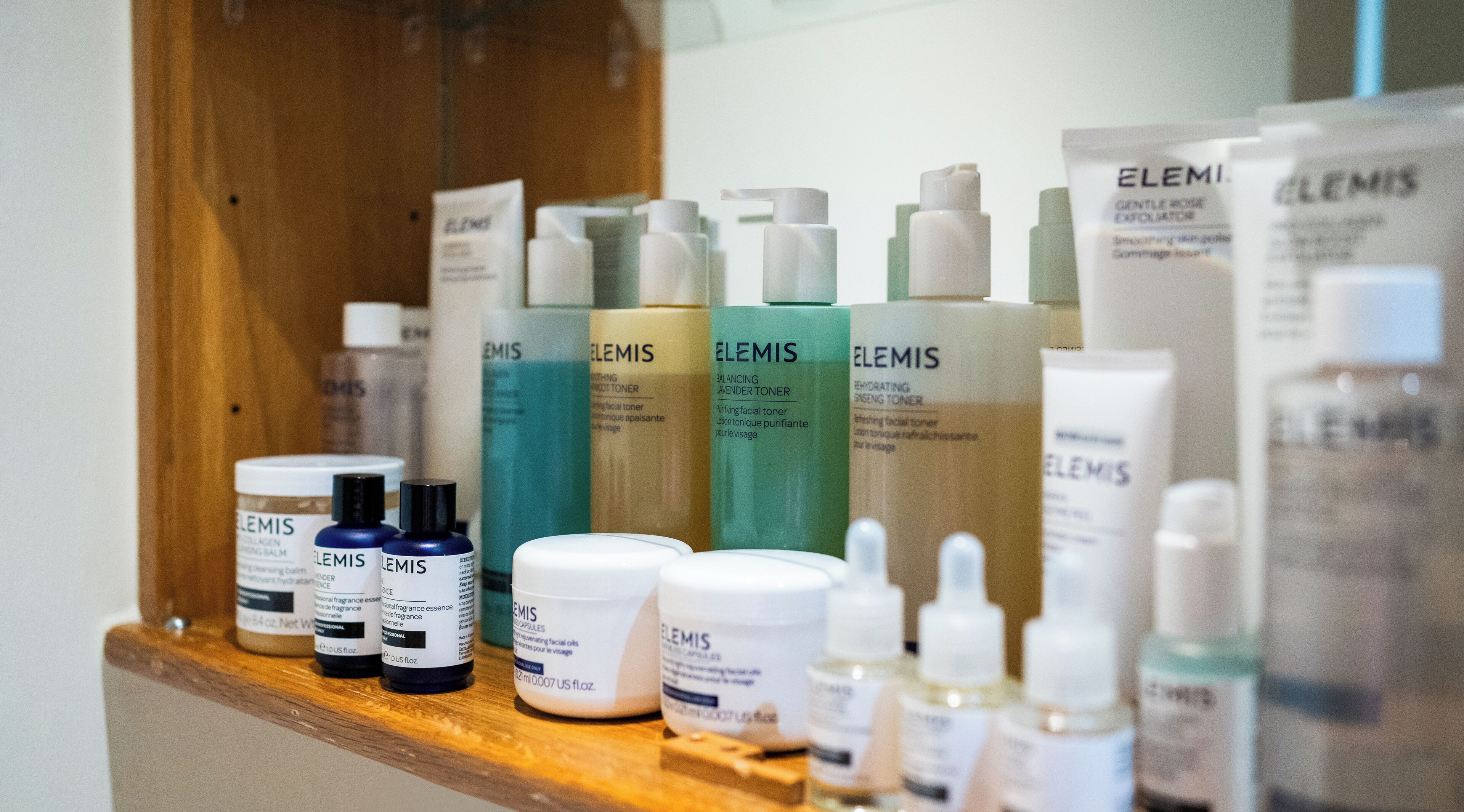 A variety of skincare products on a wooden shelf.