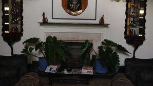 A living room with a fireplace, two large mirrors, and a framed coat of arms above the mantel. - Hotel Regency (Lima)