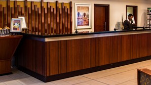 A reception desk with a wooden panel design, framed artwork, and a digital screen.