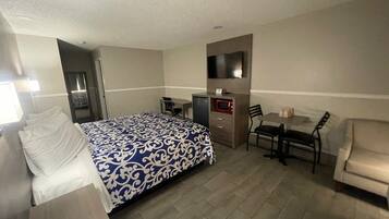 A hotel room with a bed, a desk, a TV, a microwave, and a sofa.