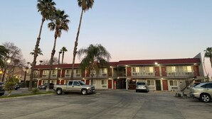 Un motel avec un toit rouge, plusieurs étages et un parking où sont garées plusieurs voitures.
