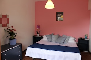 Un dormitorio con cama, dos mesitas de noche, un aparador, un aplique de pared y un cuadro enmarcado.