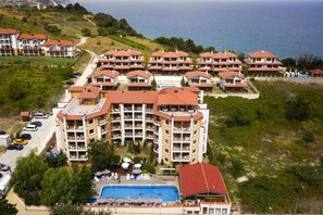 Un complex turístic amb diversos edificis, una piscina i vistes al mar.