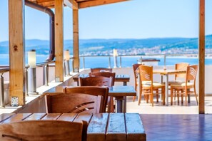 Une terrasse dotée de tables et de chaises en bois, offrant une vue sur le paysage urbain de la côte.