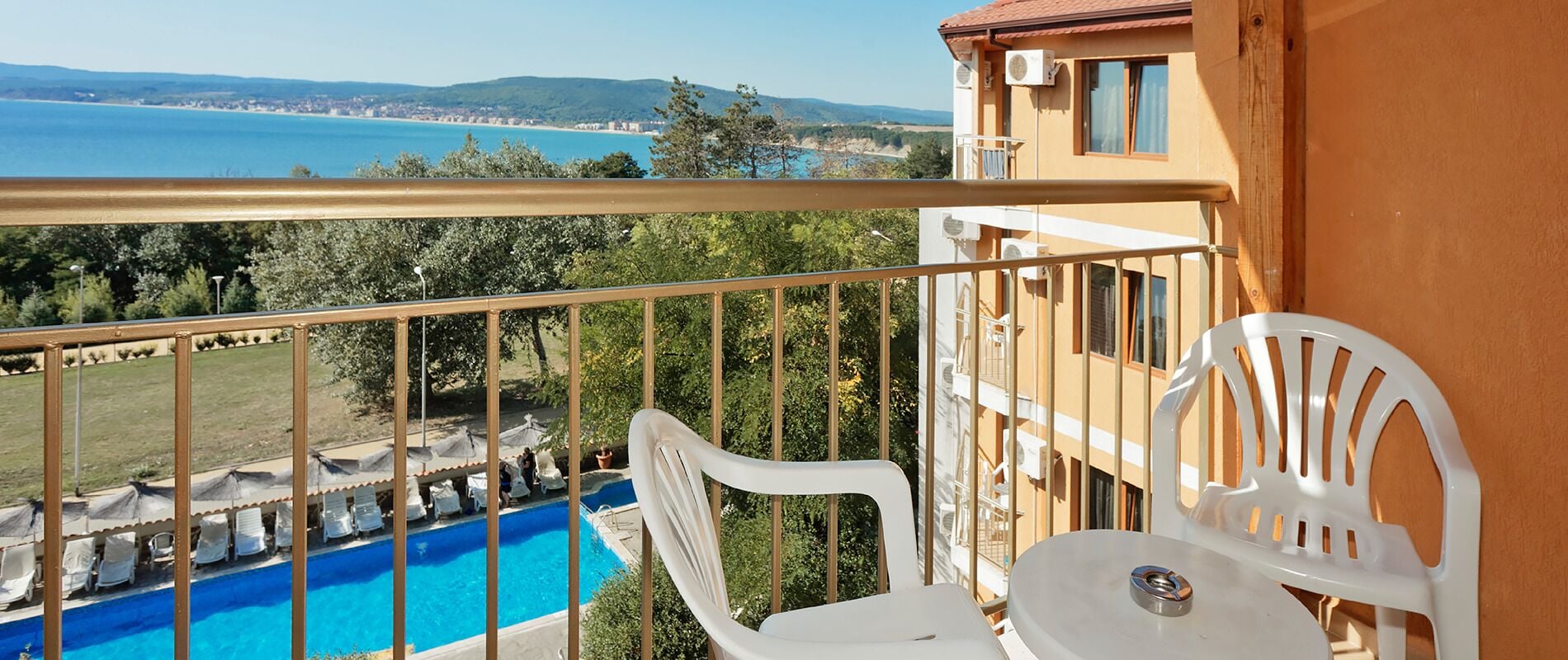Un balcón con vistas a una piscina y al mar.