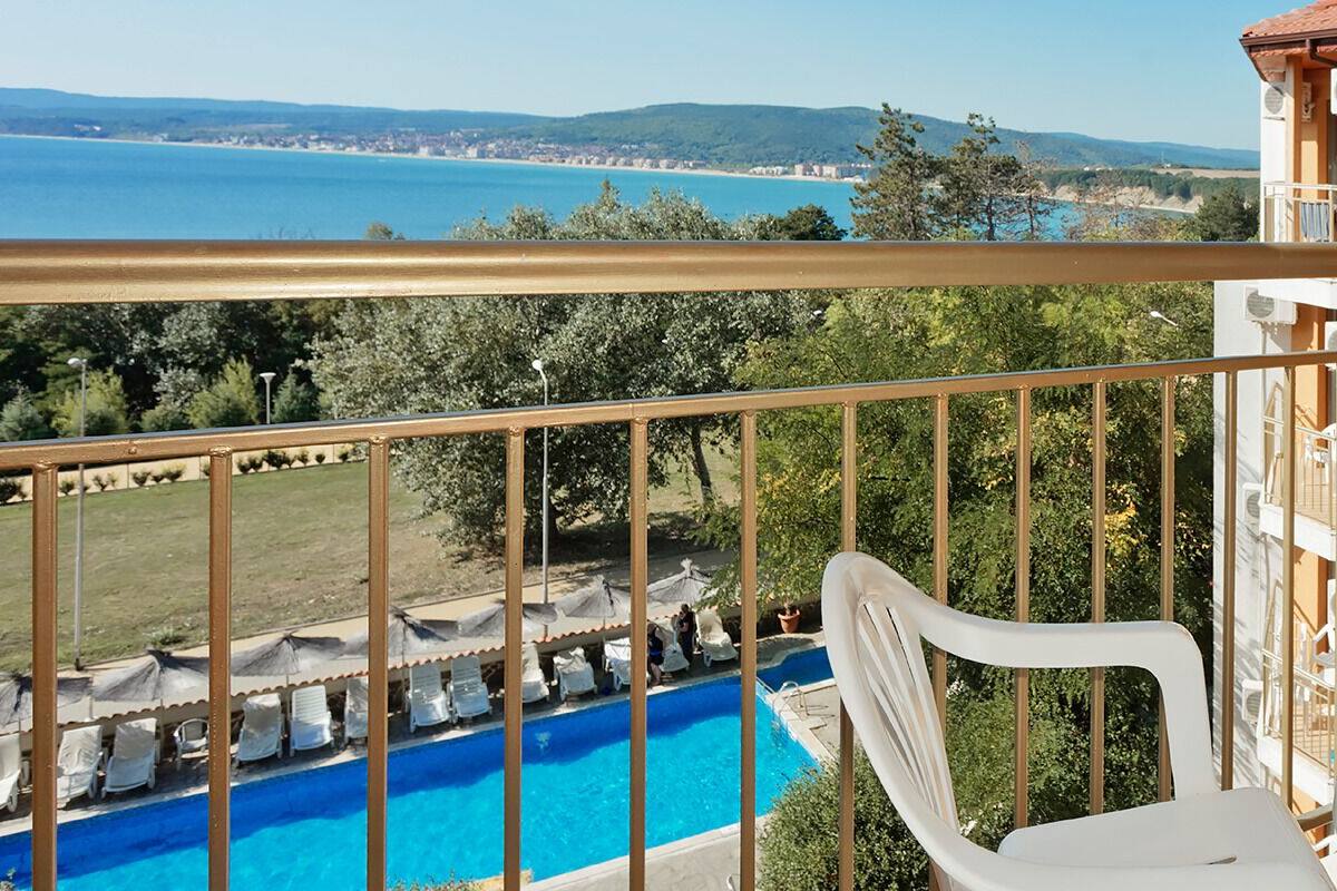 A balcony with a view of a swimming pool and the sea.