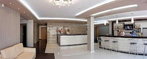 Un moderno vestíbulo de hotel con una recepción, una zona de bar y un área de estar.