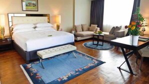 Una habitación de hotel con una cama grande, un sofá, una mesita y un escritorio.