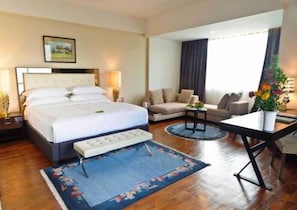 A hotel room with a large bed, a sofa, a small table, and a desk. - Himalaya (Lalitpur)