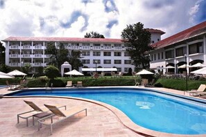 A swimming pool with lounge chairs, a building with multiple balconies, and umbrellas. - Himalaya (Lalitpur)
