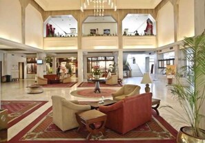 A spacious lobby with high ceilings, a central seating area with armchairs and a coffee table, and a staircase leading to an upper level. - Himalaya (Lalitpur)