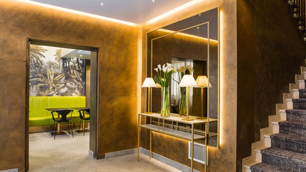 A modern interior with a staircase, a console table with lamps, and a seating area with a green sofa and chairs. - Venice Maggior Consiglio (Venice)