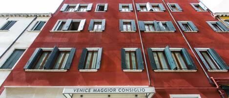 Un edificio rojo con múltiples ventanas y un letrero que dice "VENICE MAGGIOR CONSIGLIO".