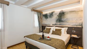 Quarto de hotel moderno com uma cama grande, uma mesa de cabeceira, uma obra de arte na parede e piso de madeira.