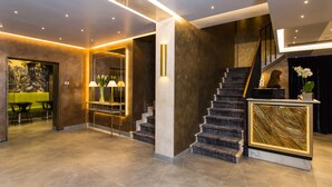 A modern lobby with a staircase, a reception desk, and a seating area. - Venice Maggior Consiglio (Venice)