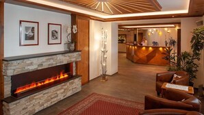 A lobby with a stone fireplace, a reception desk, leather seating, and a modern ceiling design.