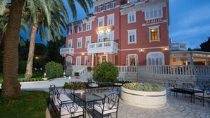 Un hotel de varios pisos con fachada roja, balcones y zonas de estar al aire libre.
