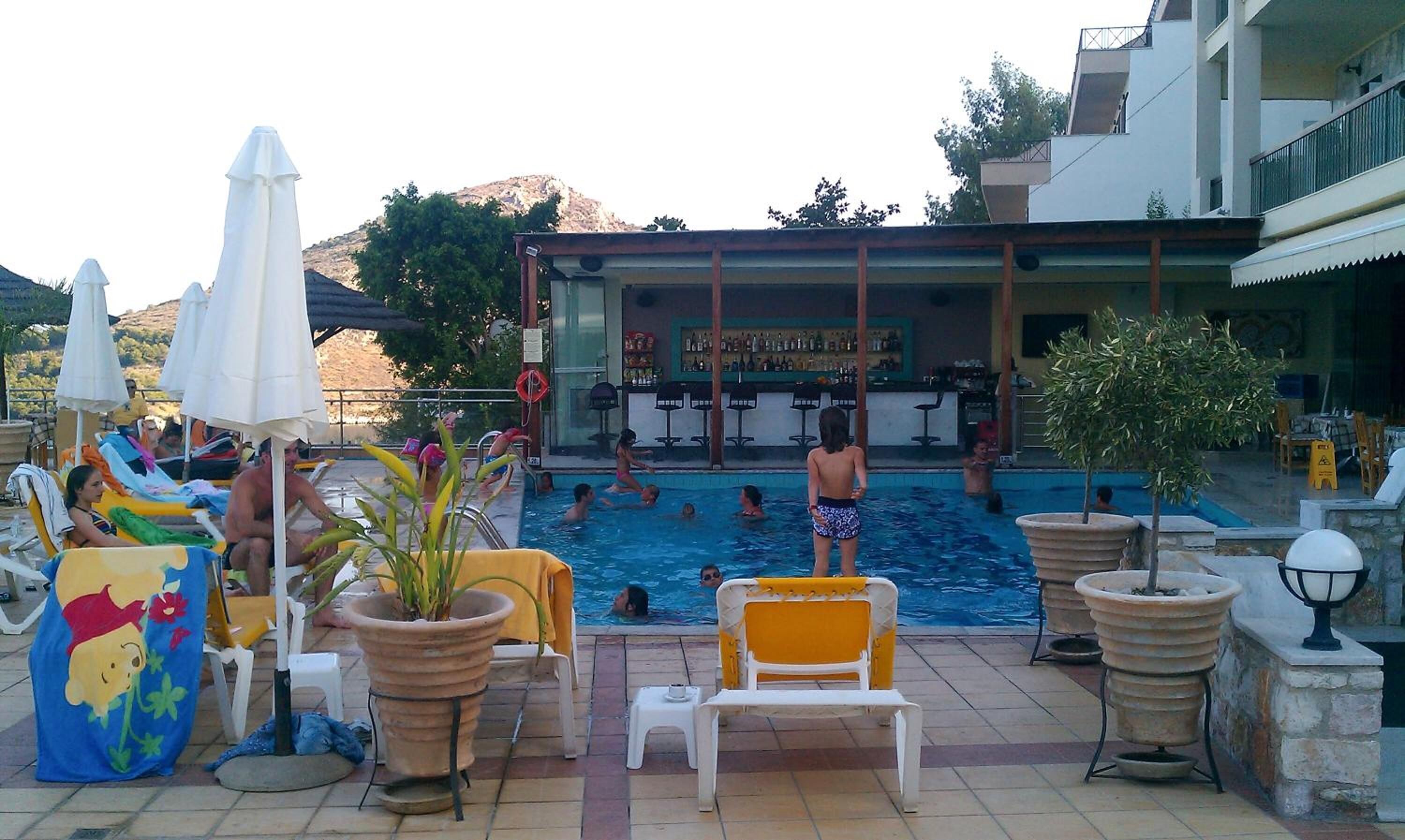 Zona de piscina con sillones reclinables, sombrillas y un bar.