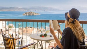 A balcony with a view of the sea, a table with a book, and a chair. - John & George (Nafplio)