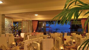 A restaurant with tables set for dining, featuring a view of the ocean. - John & George (Nafplio)