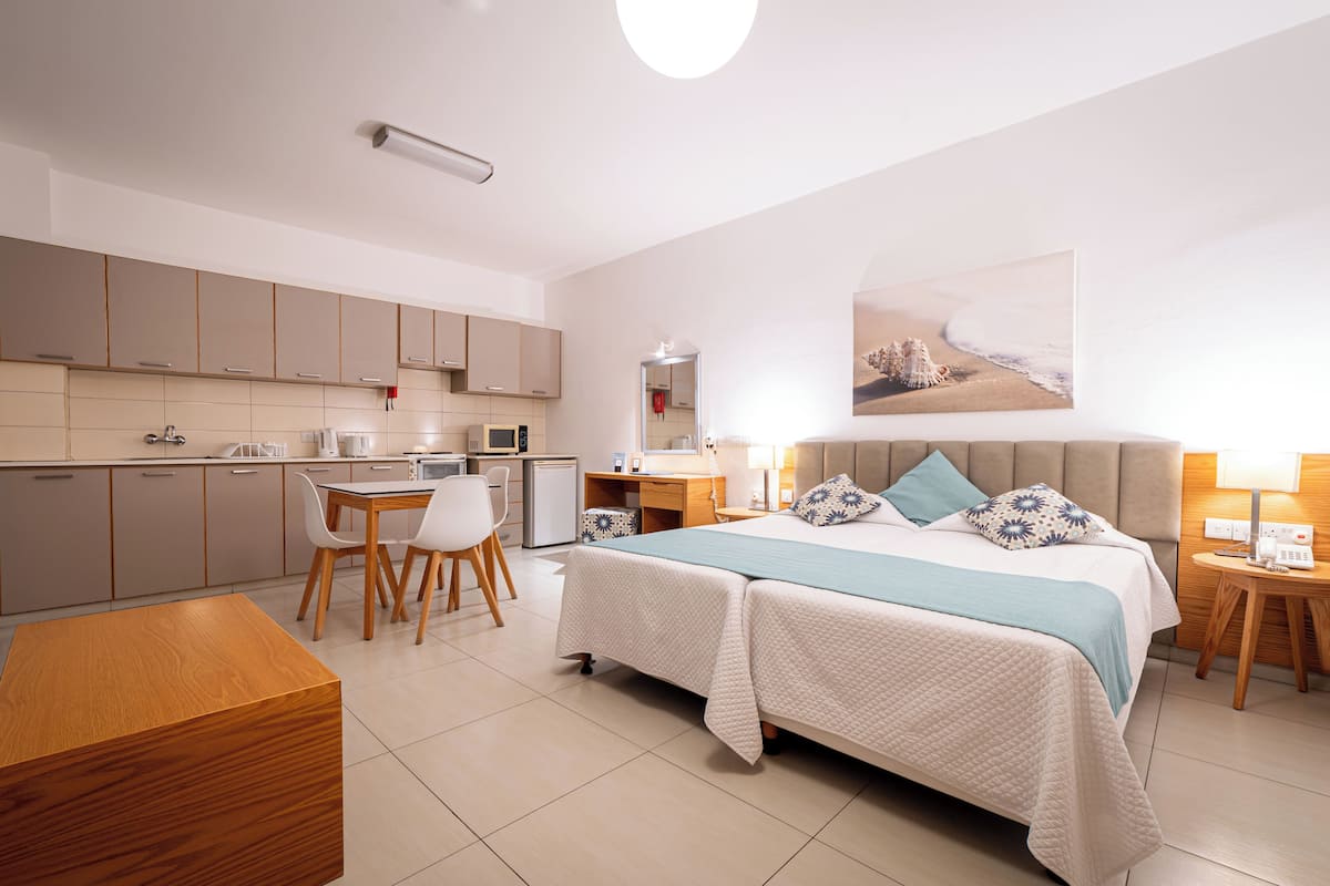 Une chambre d’hôtel moderne équipée d’un lit, de tables de chevet, d’un bureau et d’une kitchenette.