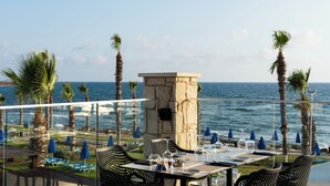 Un restaurante frente al mar con terraza, un pilar de piedra y vistas al océano.
