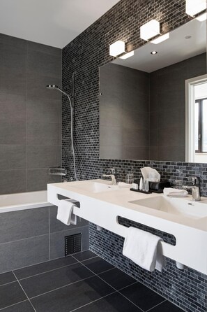 Une salle de bain moderne avec un grand miroir, deux lavabos et une douche.