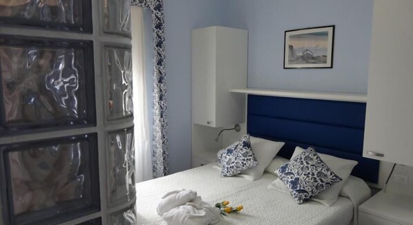A hotel room with a bed, a white headboard, a wall-mounted cabinet, and a framed picture. - Hotel La Gioiosa (Rimini)