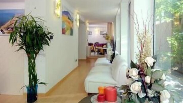 A modern living room with a white sofa, a coffee table with candles, and a large window with a view of greenery.
