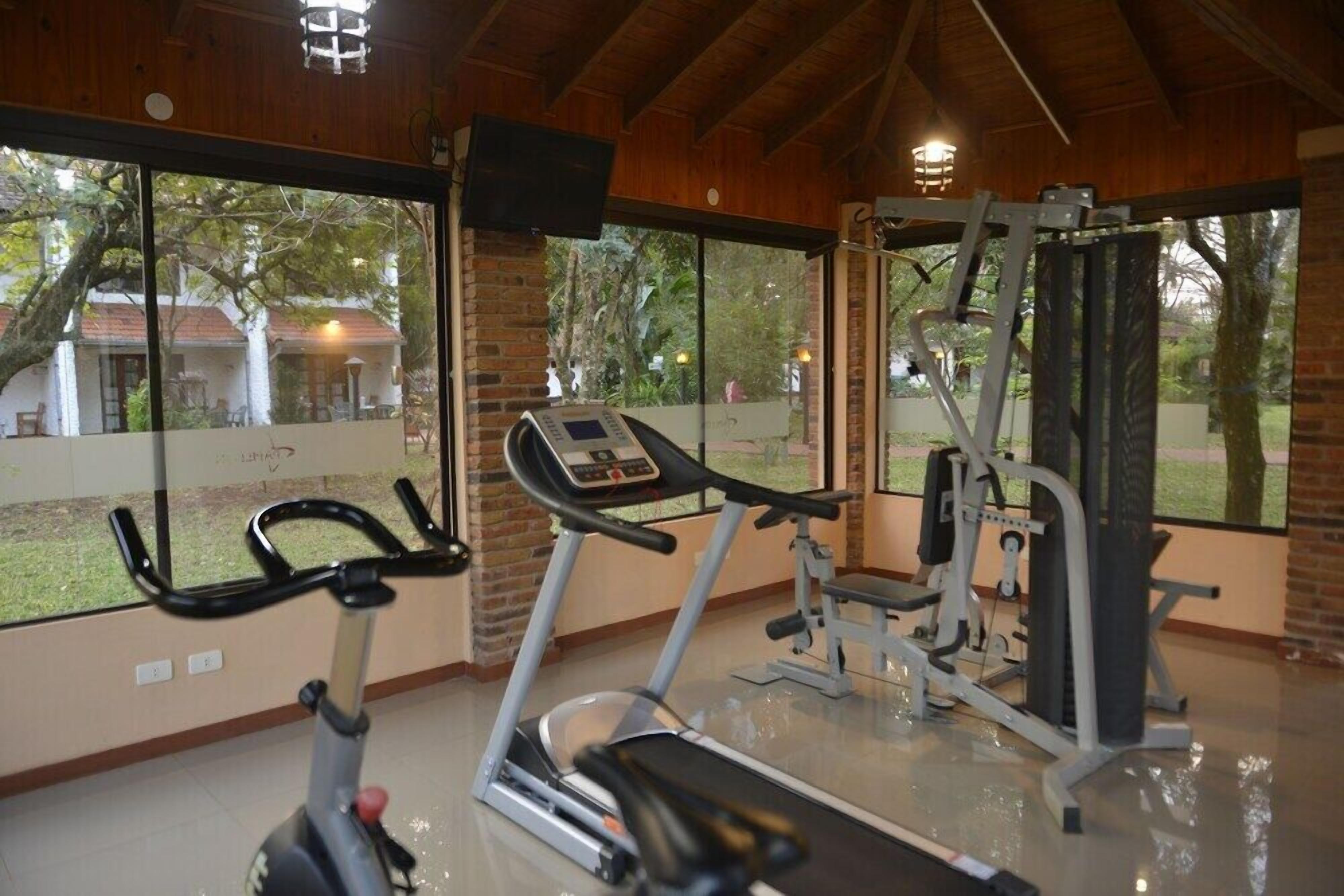 A gym with exercise equipment, large windows, and a view of the outside.