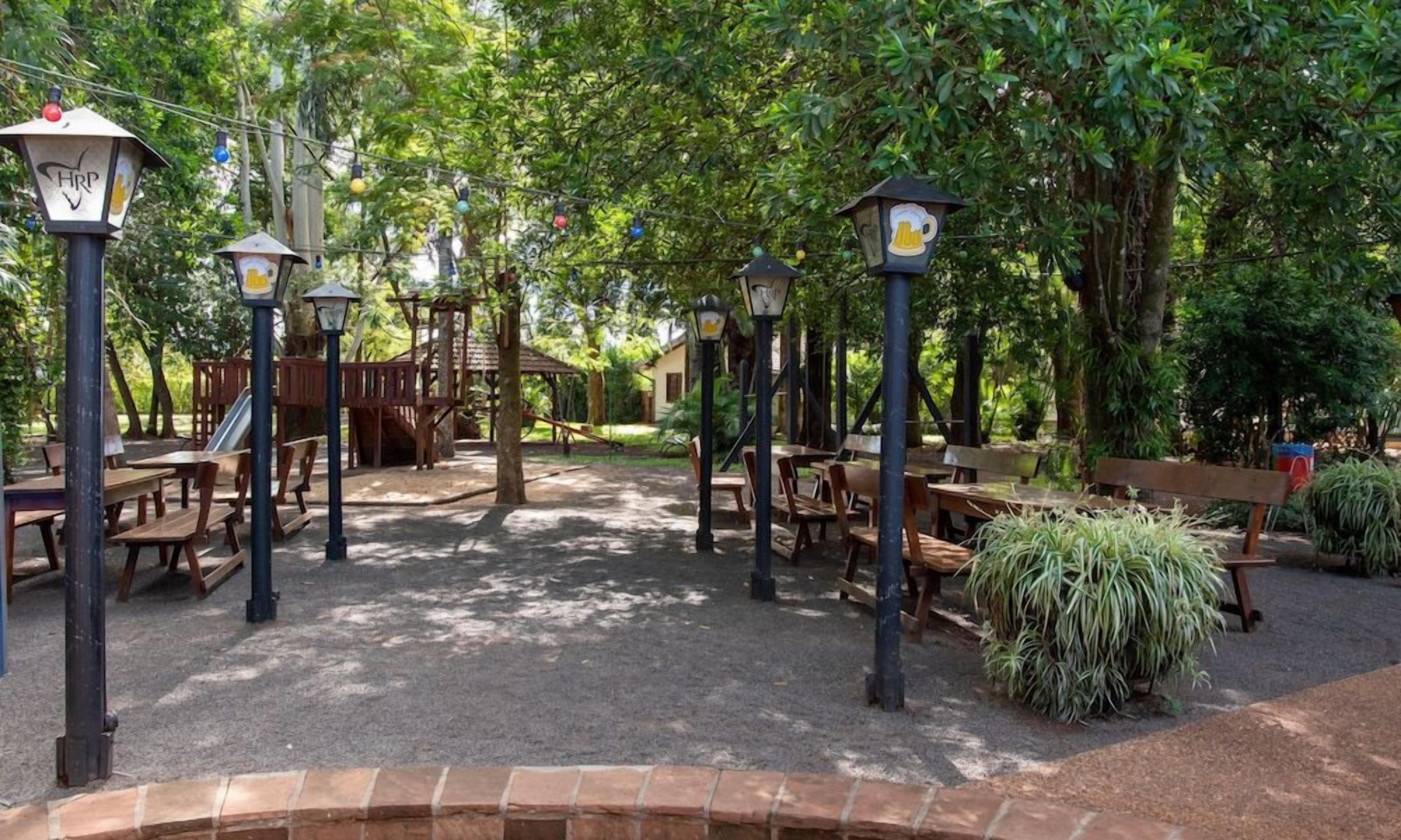 Un espacio al aire libre con mesas de picnic y bancos, rodeado de árboles y follaje.