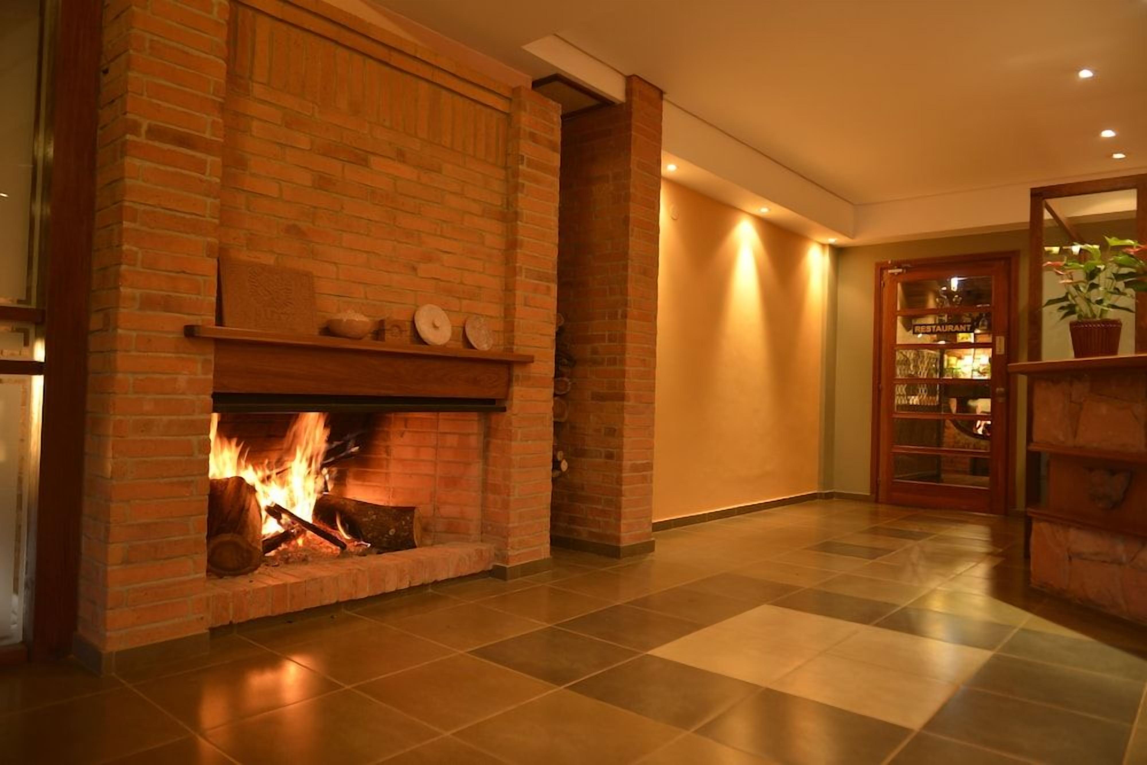 Una chimenea con pared de ladrillo, piso de baldosas y puerta que da a un restaurante.