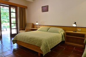 A bedroom with a bed, bedside tables, a chair, and a door leading to an outdoor area.