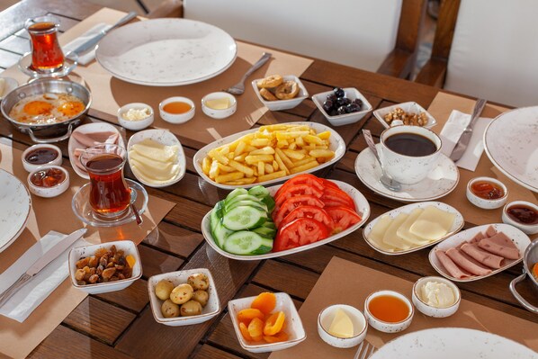 Una mesa dispuesta con diversos platos, incluyendo papas fritas, pepinos, tomates y carnes, junto con salsas y bebidas.