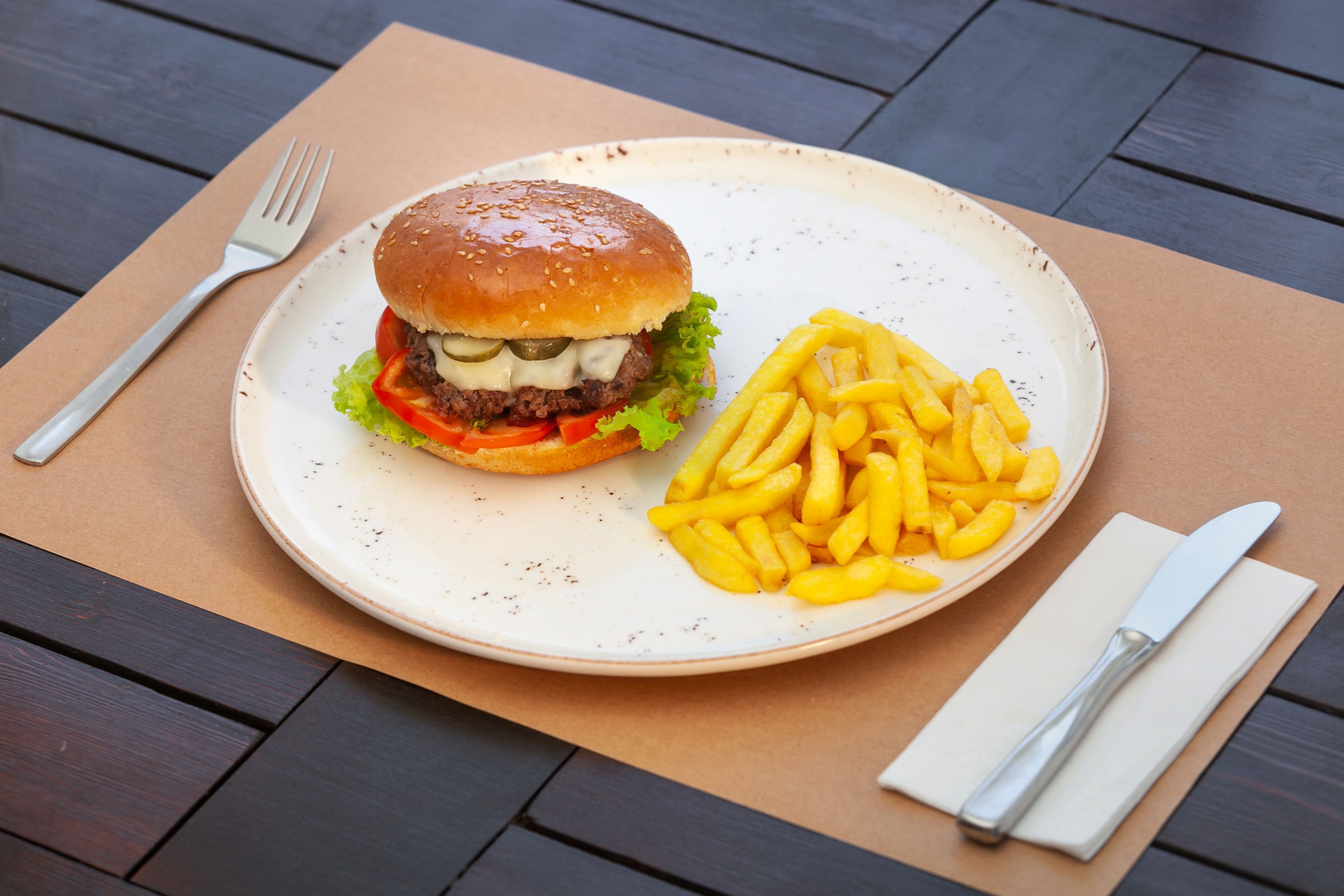 Un plato con una hamburguesa y papas fritas sobre una mesa de madera.