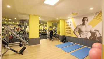 Un gimnasio con equipamiento de ejercicio, colchonetas azules y decoración inspiradora en las paredes.