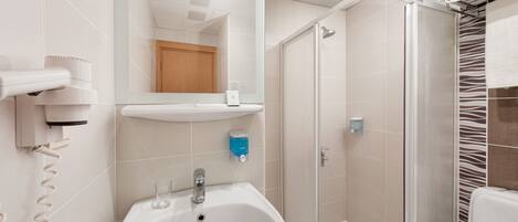 Un baño moderno con lavamanos blanco, un espejo, ducha y toallero.