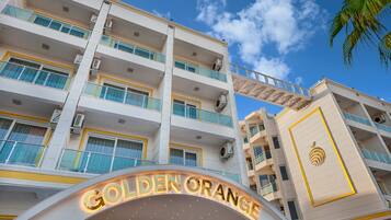 Un hotel de varios pisos con balcones y un llamativo letrero que dice 'Golden Orange'.